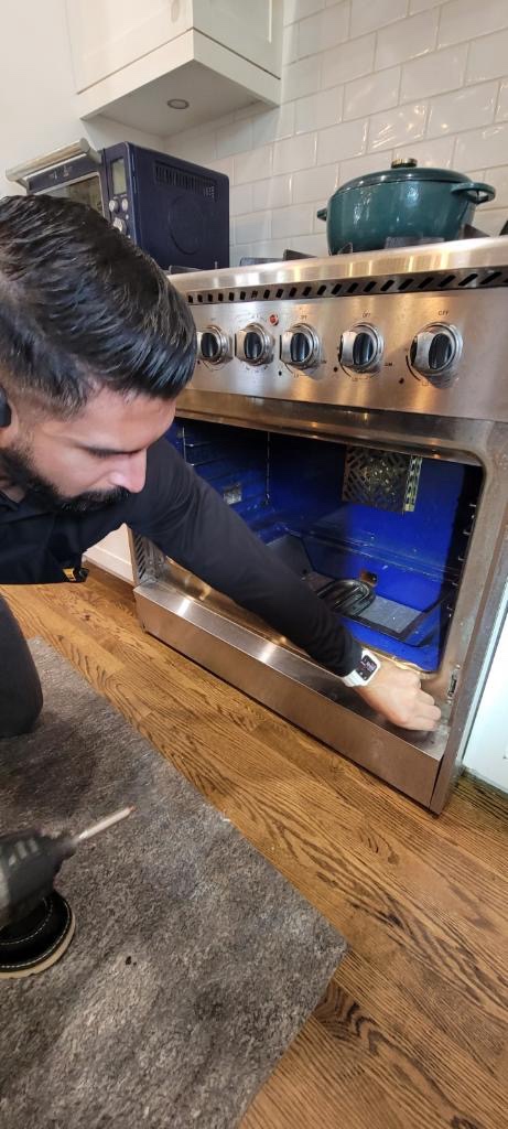 Technician inspecting gas range oven in residential kitchen