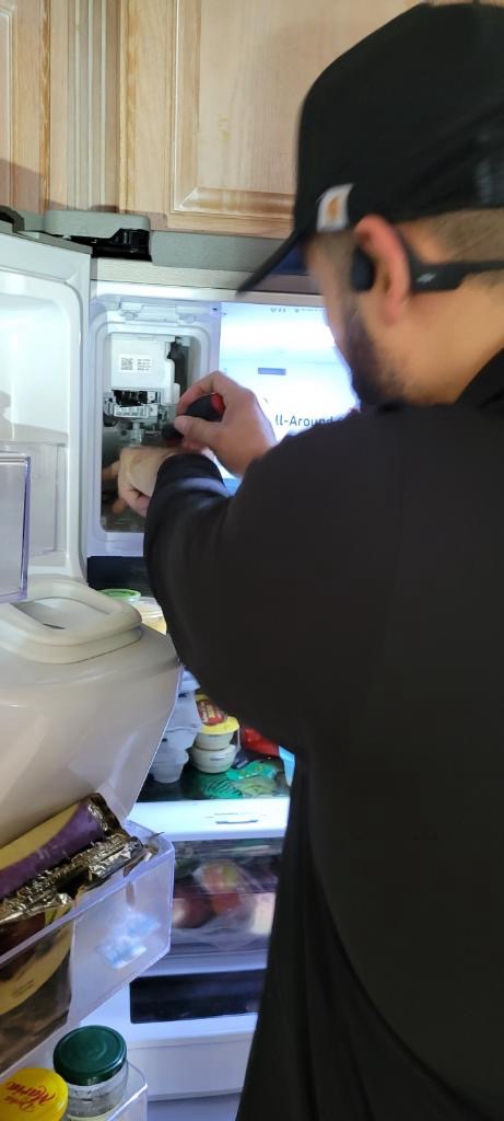 Technician repairing refrigerator ice maker in customer home